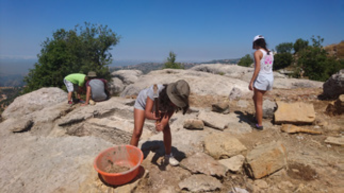 Youth doing preliminary archaeological site cleaning tasks